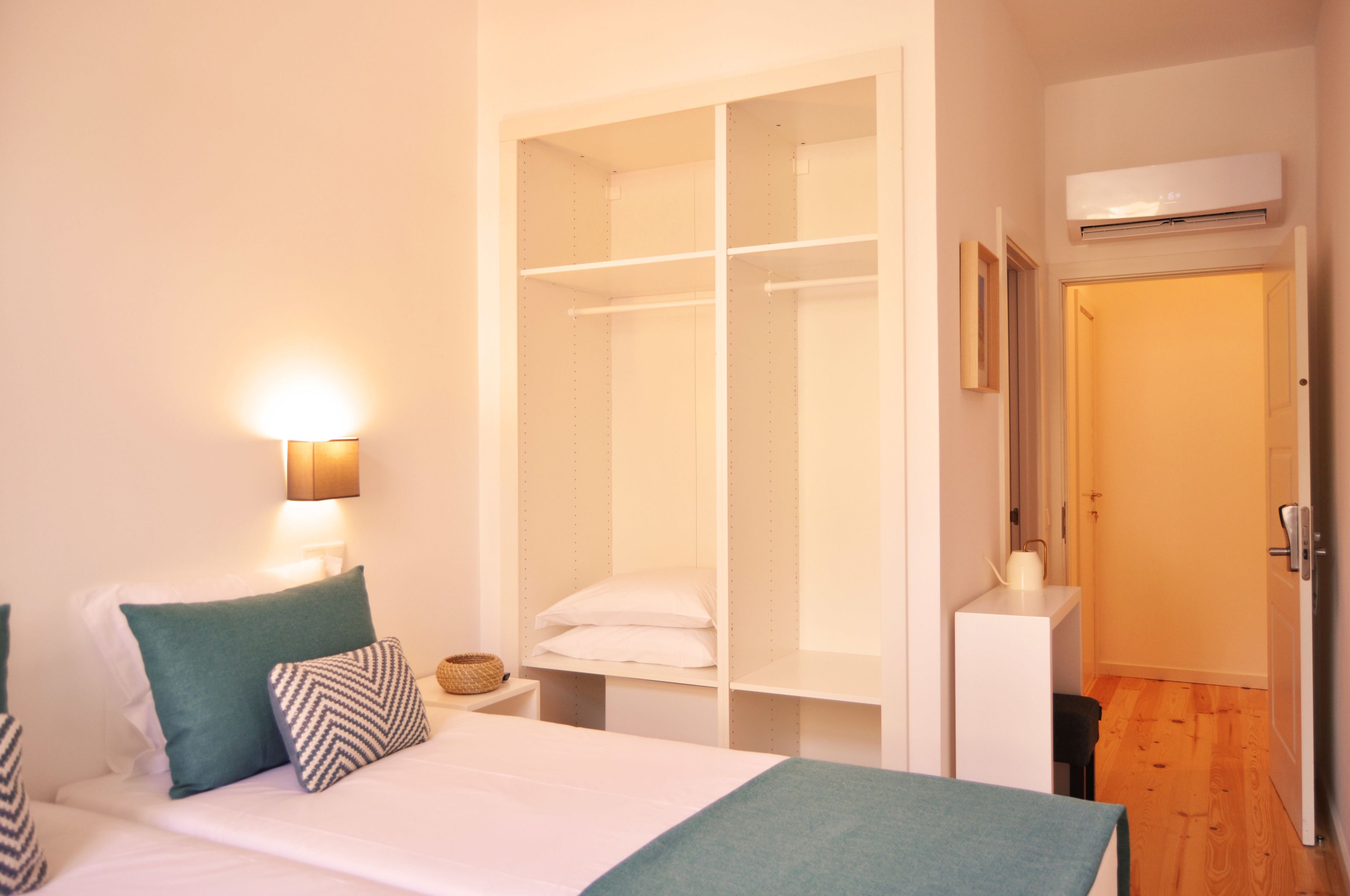 Een hotelkamer met een bed, een kledingkast, een nachtkastje en een airconditioning.