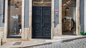Fachada de hotel con una entrada central que presenta una reja de hierro decorativa, dos ventanas en la parte superior y un cartel con el nombre del hotel.