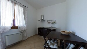 A small, clean kitchen with a dining table, chairs, and a radiator. - Agriturismo Cà Pisani (Porto Viro)
