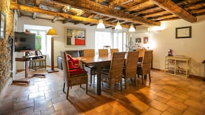 Un coin repas rustique avec une table et des chaises en bois, un téléviseur et une lampe.