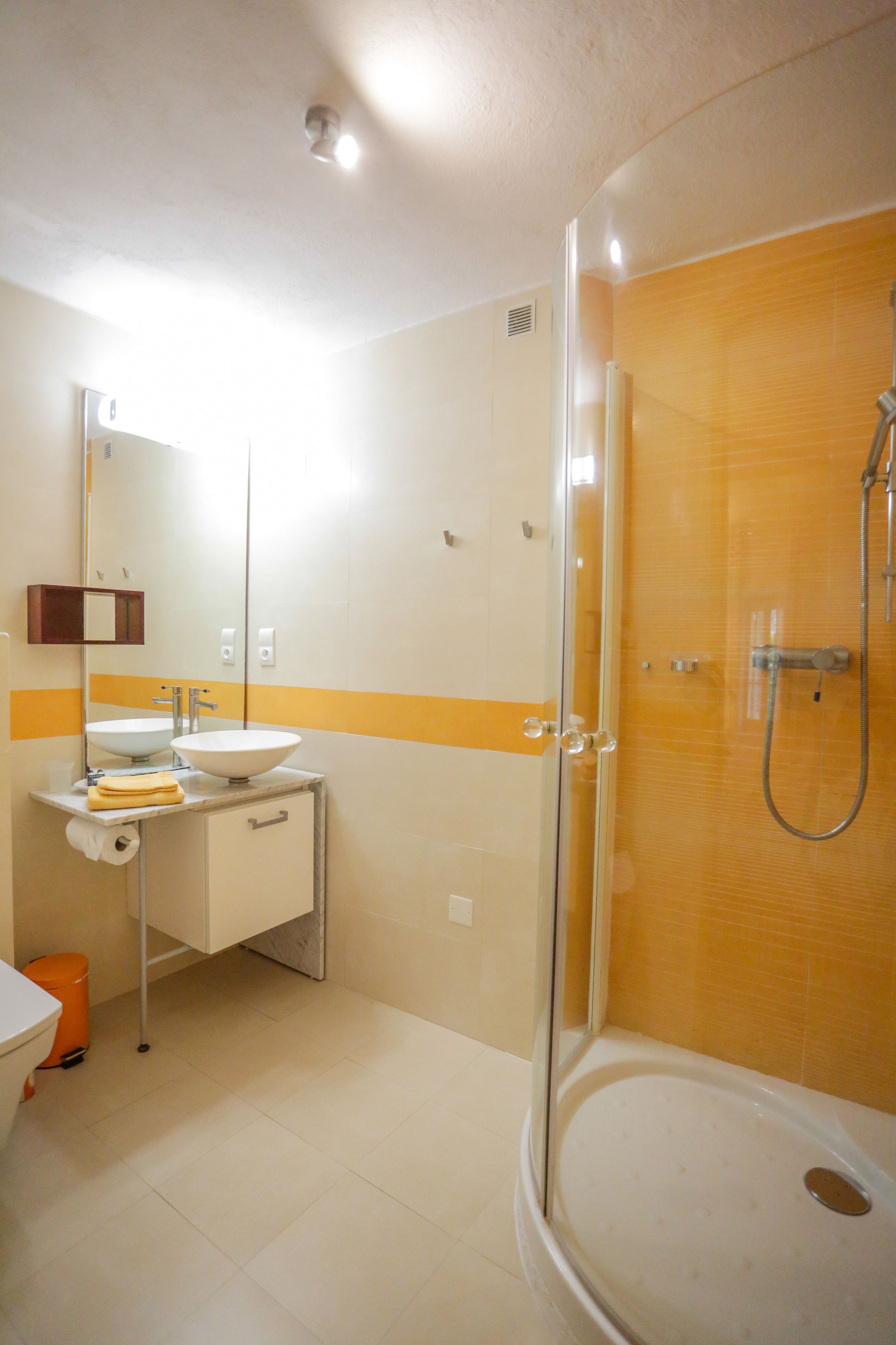 A bathroom with a glass-enclosed shower, a sink with a mirror, and a toilet.