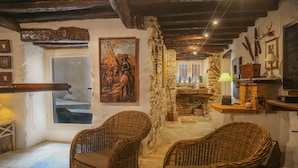 Un intérieur rustique avec des meubles en osier, des murs en pierre et un tableau.