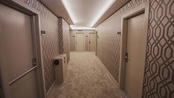 A hallway with patterned walls, a carpeted floor, and doors leading to rooms.