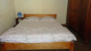 Un dormitorio con una cama de madera, una mesita de noche con lámpara y un armario.