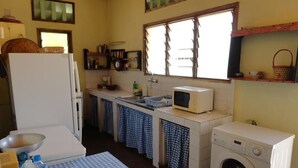 Una cocina compacta equipada con refrigerador, microondas, lavadora y pileta.