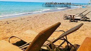 A beach with lounge chairs and a pier extending into the ocean. - Royal City Hotel (Antalya)