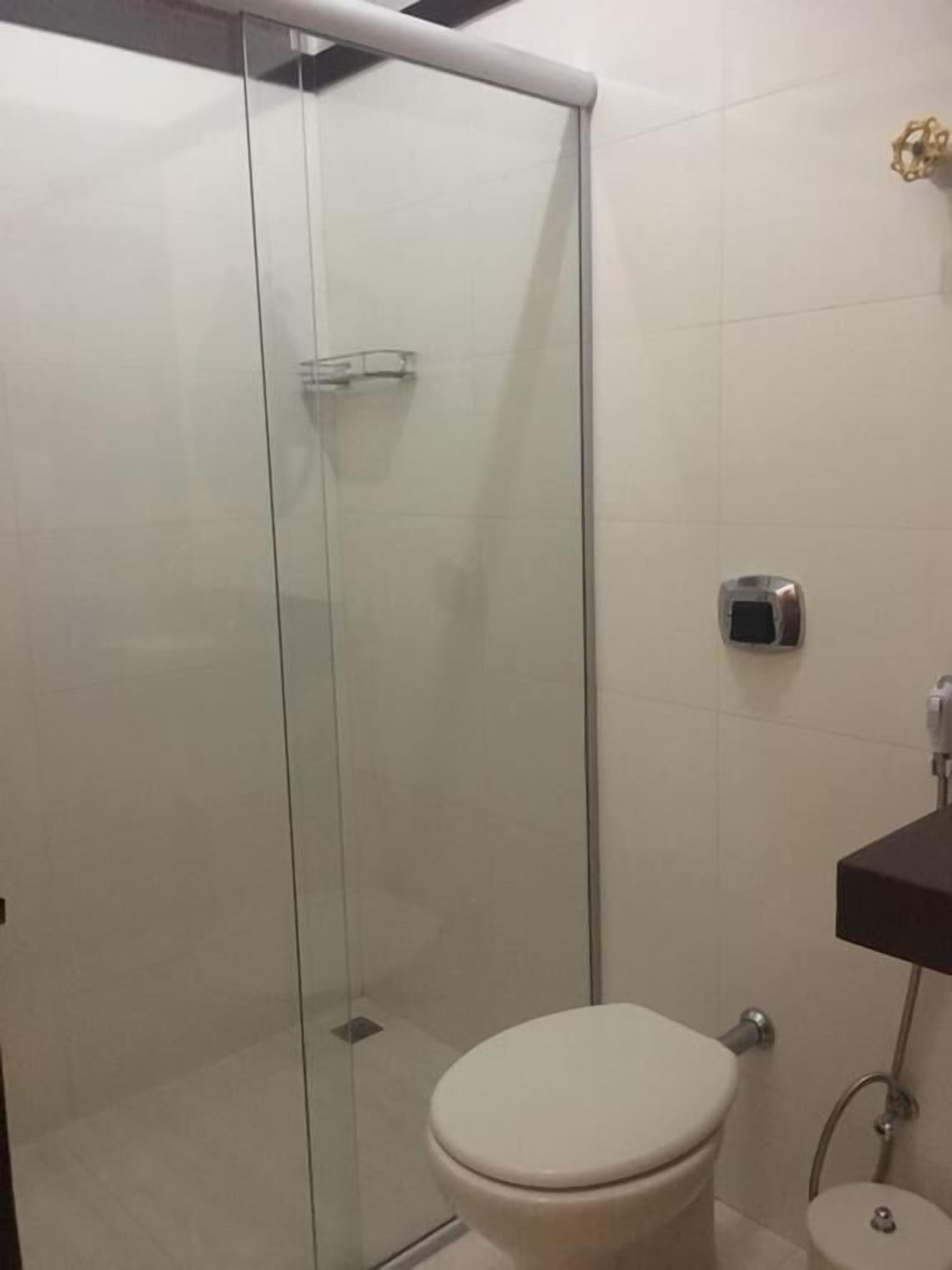 Une salle de bain avec une douche à parois de verre, des toilettes et un lavabo avec un robinet.
