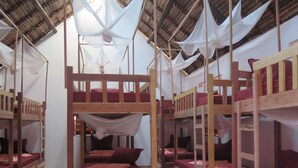 Um quarto com beliches, móveis de madeira e telhado de palha.