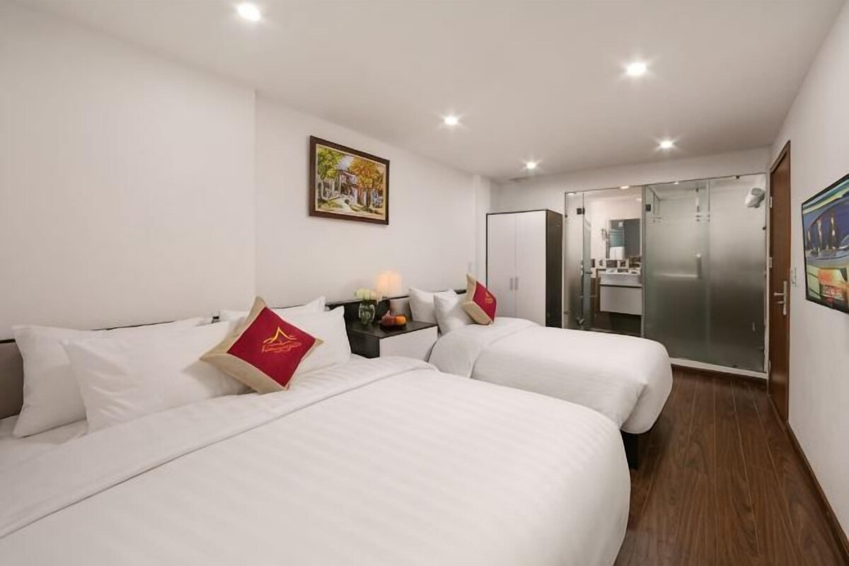 Een hotelkamer met twee bedden, een tafeltje met een lamp, een spiegel en een kledingkast.