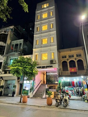 A multi-story building with a central entrance, a visible staircase, and a storefront with clothing items.
