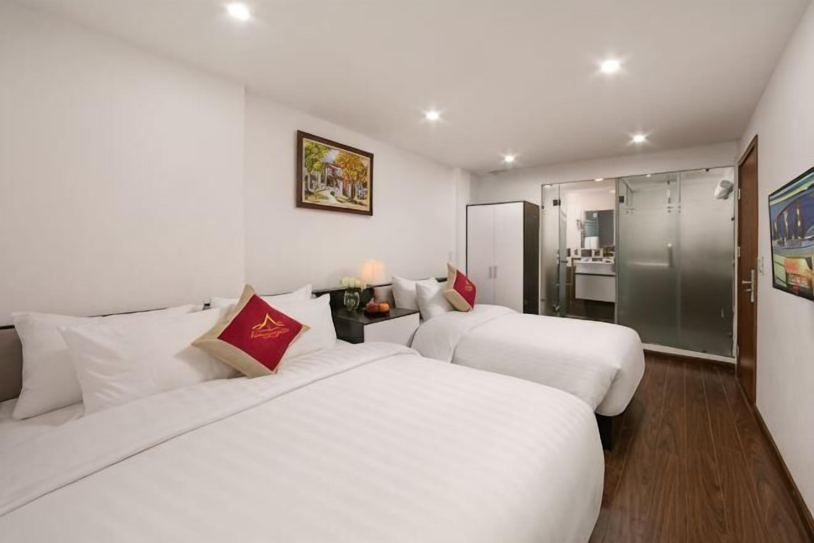Ein Hotelzimmer mit zwei Betten, einem kleinen Tisch mit Lampe, einem Spiegel und einem Kleiderschrank.