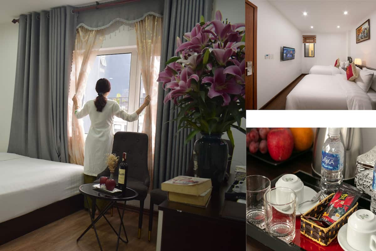 A hotel room with a bed, a desk with a vase of flowers, a chair, and a window with curtains.