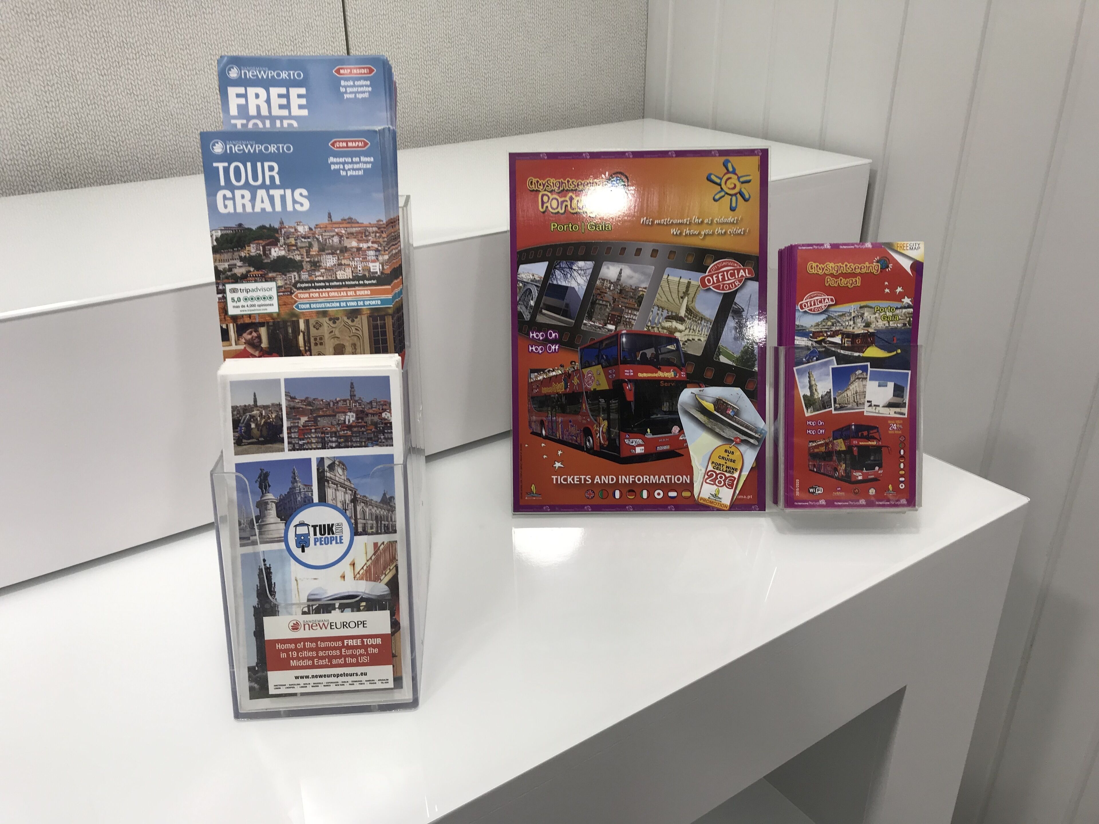 A display of travel brochures for tours in Porto, including a free tour and a city sightseeing tour.
