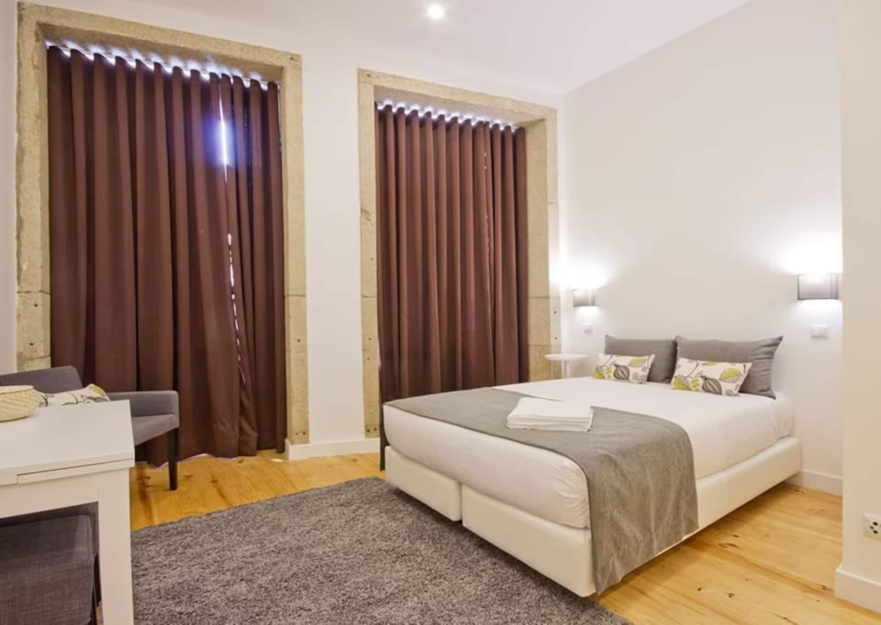 A modern bedroom with a bed, bedside tables, and curtains.