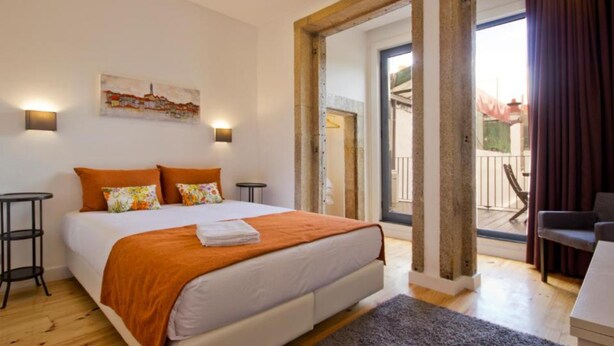 A modern bedroom with a large bed, two bedside tables, a nightstand, and a view of the balcony. - MyStay Porto Bolhão (Porto)