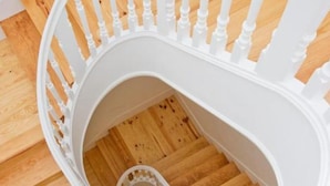 A spiral staircase with white balusters and wooden steps. - MyStay Porto Bolhão (Porto)