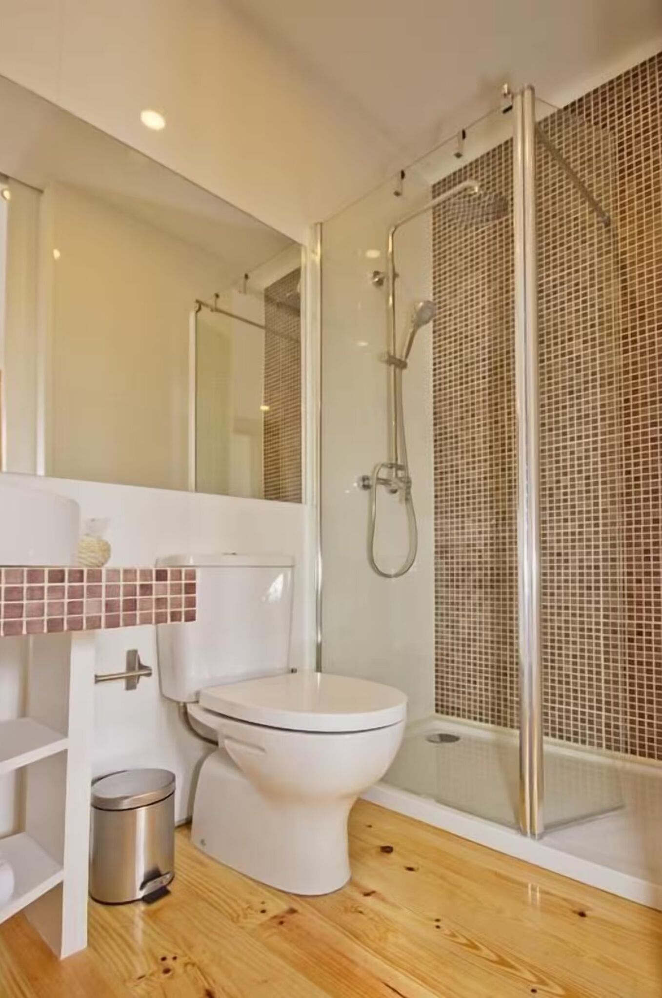 A modern bathroom with a glass-enclosed shower, a white toilet, and a tiled backsplash.