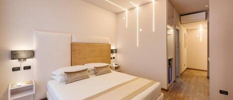 A modern hotel room with a large bed, bedside tables, and a headboard.