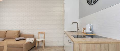 A modern kitchen with a wooden countertop, a sink, and a kettle.