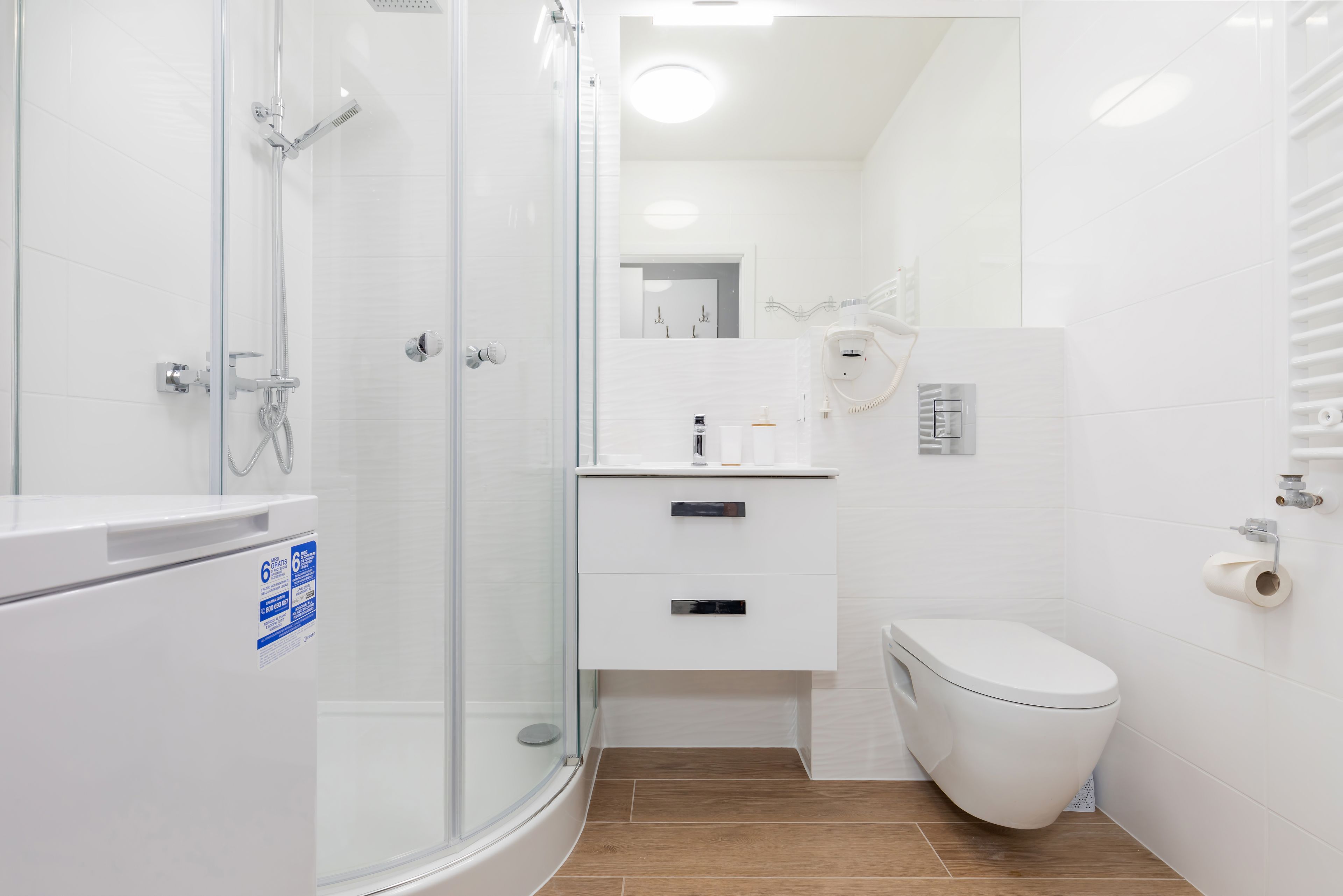 A modern bathroom with a glass shower enclosure, a toilet, and a sink with a mirror above it.
