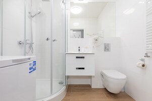A modern bathroom with a glass shower enclosure, a toilet, and a sink with a mirror above it.