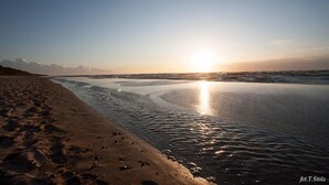 A beach with footprints leading to the water, a clear sky, and the sun setting or rising. - Villa Ula Apartament (Rewal)