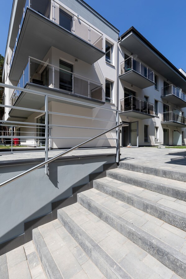 A multi-story building with a modern design, featuring a staircase with metal railings leading to an entrance. - Villa Ula Apartament (Rewal)
