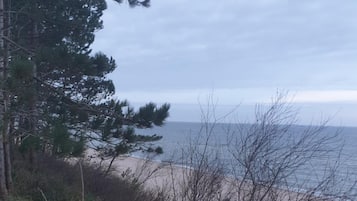 Escada que dá para uma praia, com vista para o oceano e árvores.