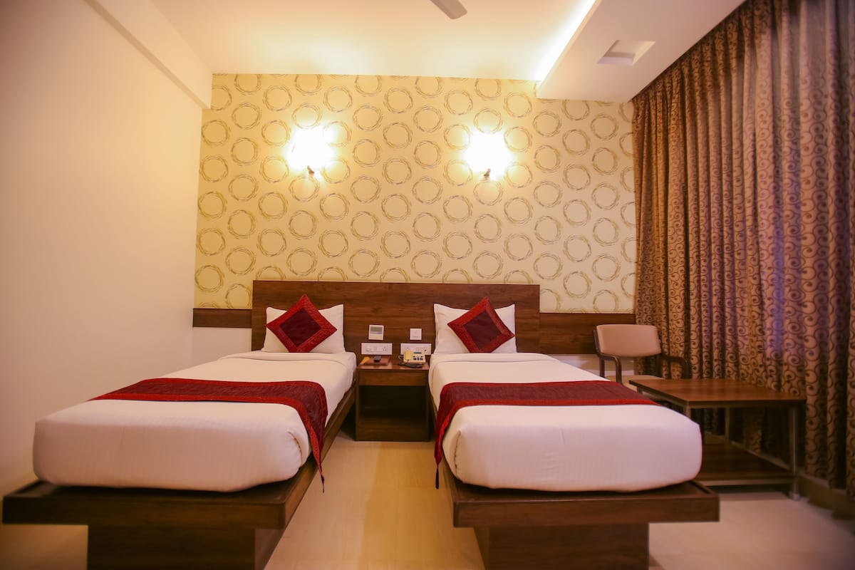 A hotel room with two beds, a nightstand, a desk, and a chair.