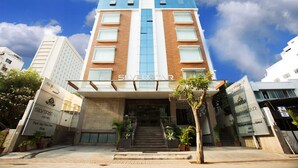 Un hotel con un diseño moderno, que presenta un llamativo letrero 'SILVERSTAR', una escalera que conduce a la entrada y plantas en macetas en la base.