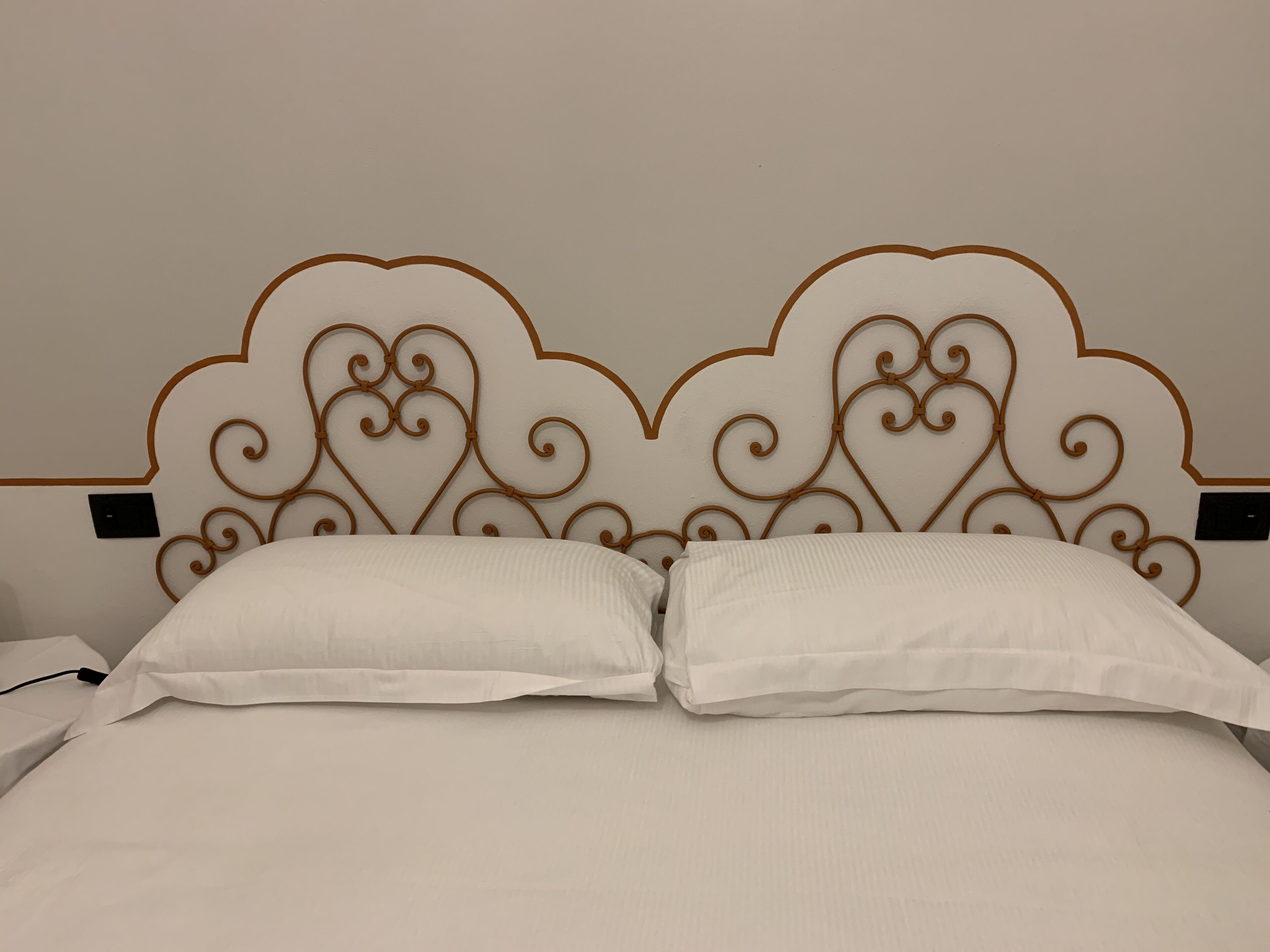 Een bed met een decoratieve hoofdbord en twee kussens.