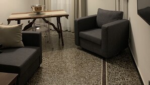 A compact living space with a sofa, a dining table, a chair, a floor lamp, and a wall-mounted TV. - Il Genovino (Genoa)