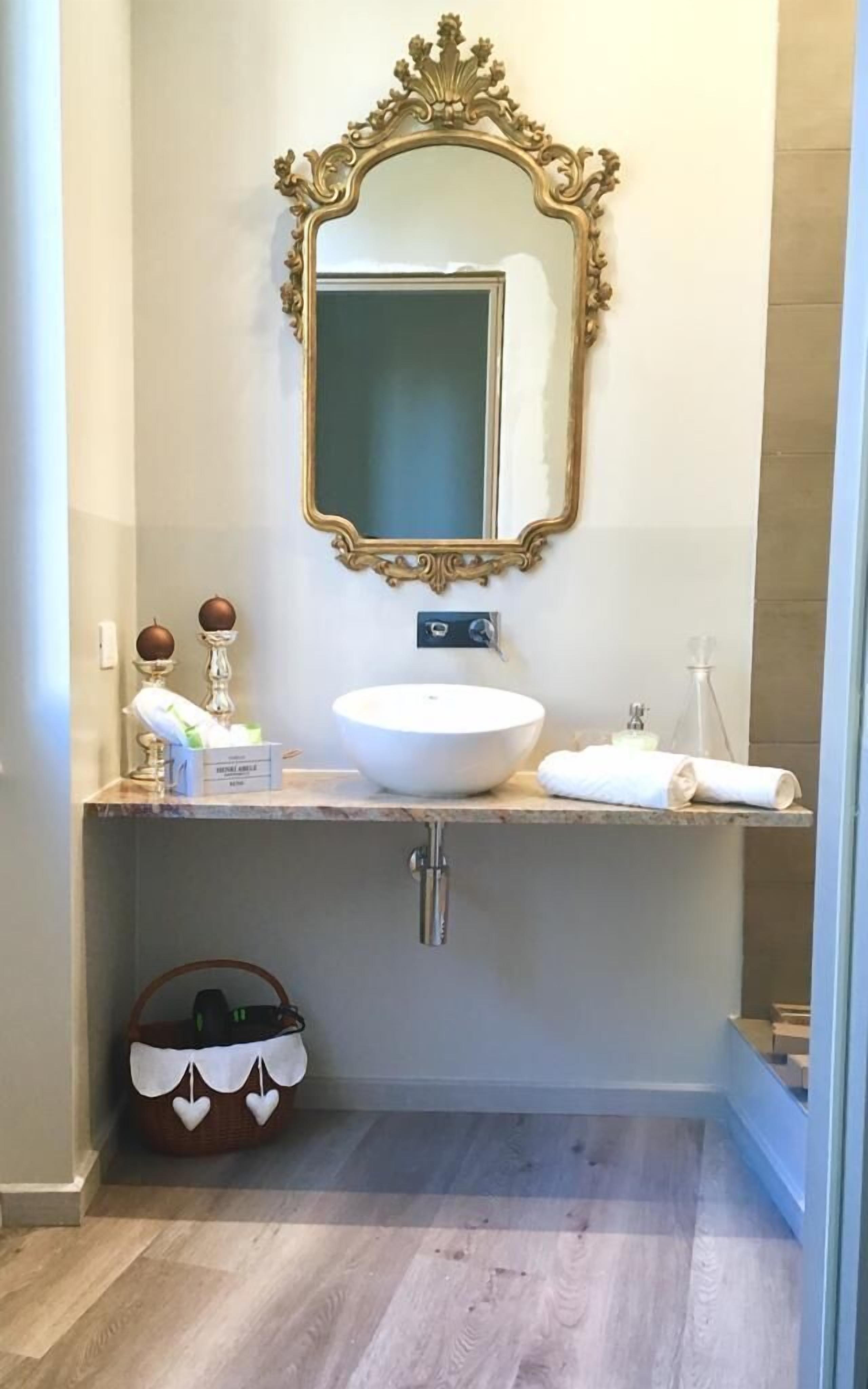 A bathroom with a large mirror, a white sink, and a vanity.