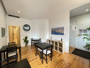 A modern hotel room with a wooden floor, a dining area with a black table and chairs, a small plant, and a painting of a bridge. - MyStay Porto Centro (Porto)