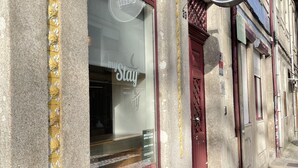 En hotels facade med et 'myStay' skilt, stenvæg og et vindue med udsigt.