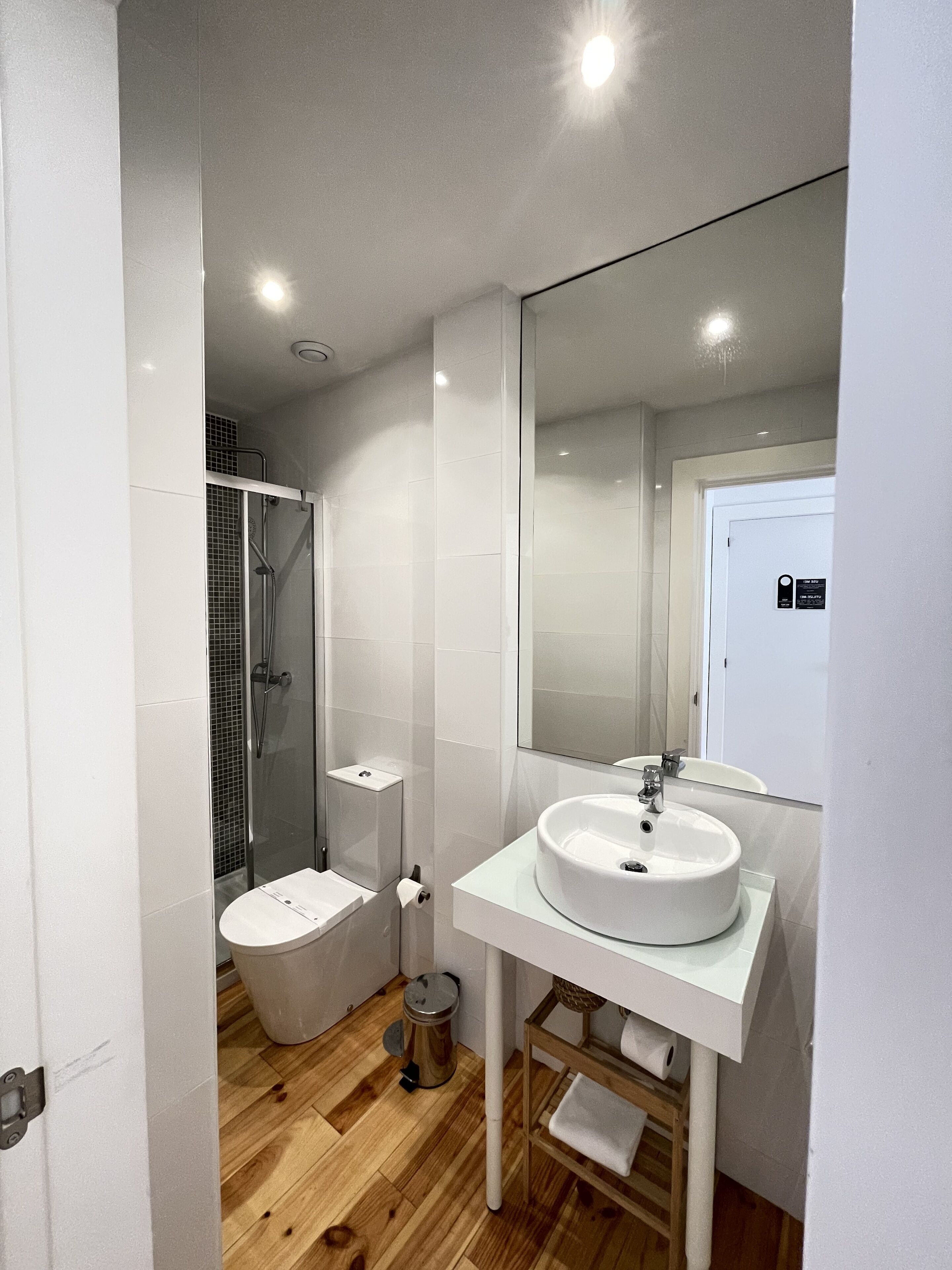 Un baño moderno con lavamanos, espejo y ducha blancos.
