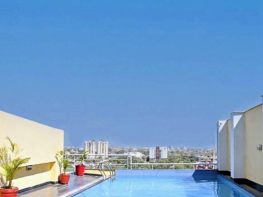 A rooftop swimming pool with potted plants and a view of the cityscape.