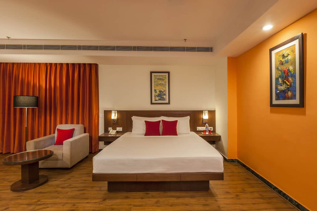 Habitación de hotel con una cama grande, un sofá, una mesa y un cuadro en la pared.