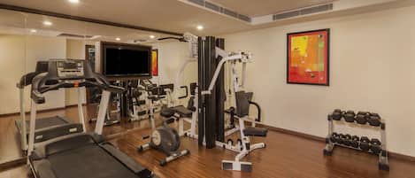A gym with treadmills, weight machines, and dumbbells.
