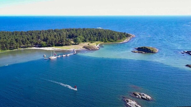 An aerial view of a coastal area with a small island, a pier, and boats. - Raet Camping (Arendal)