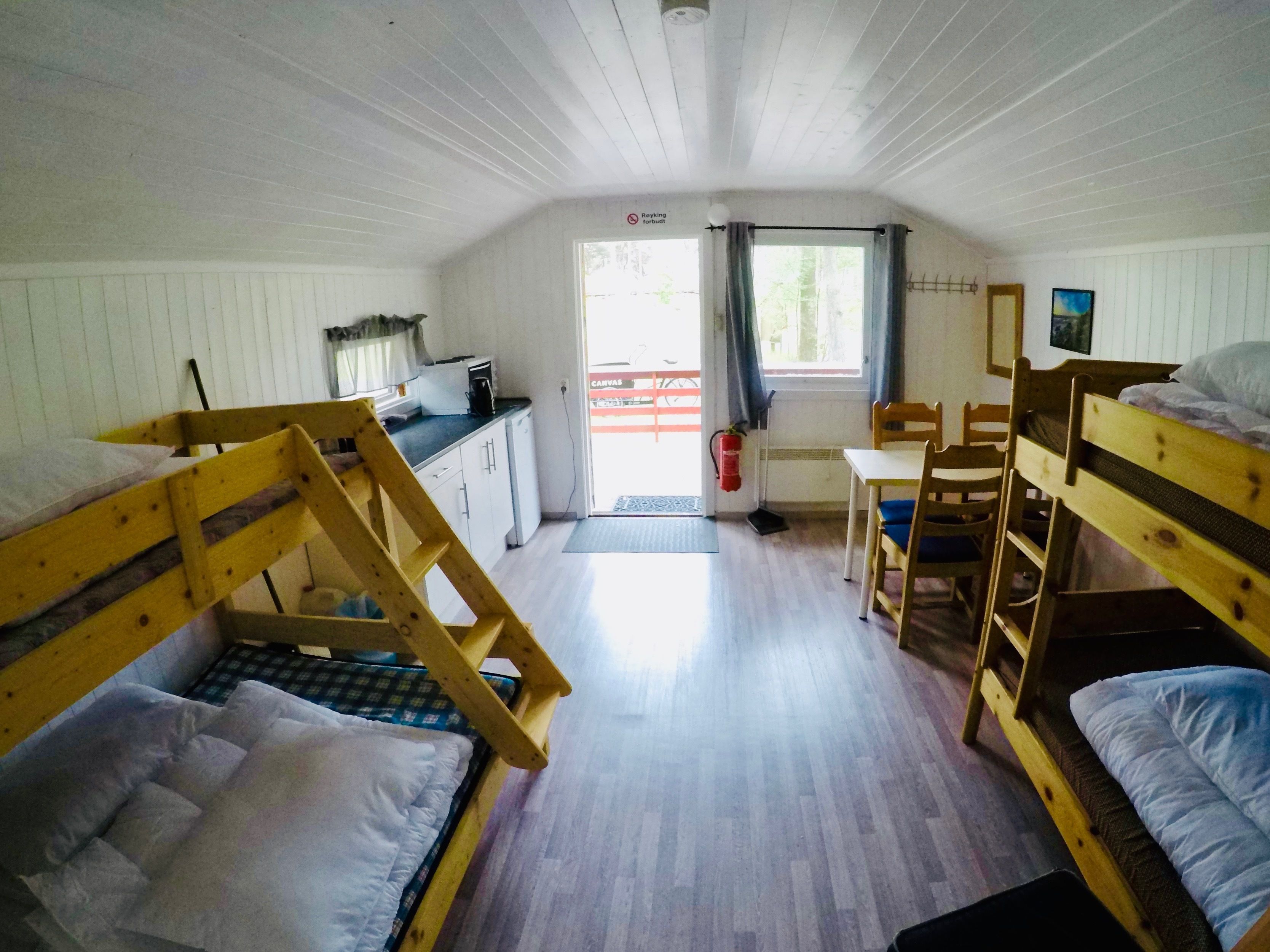 A cabin with bunk beds, a kitchenette, and a dining area.