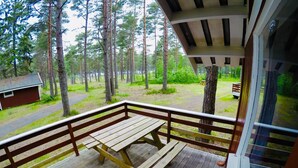 A wooden deck with a picnic table and a view of a forested area. - Raet Camping (Arendal)