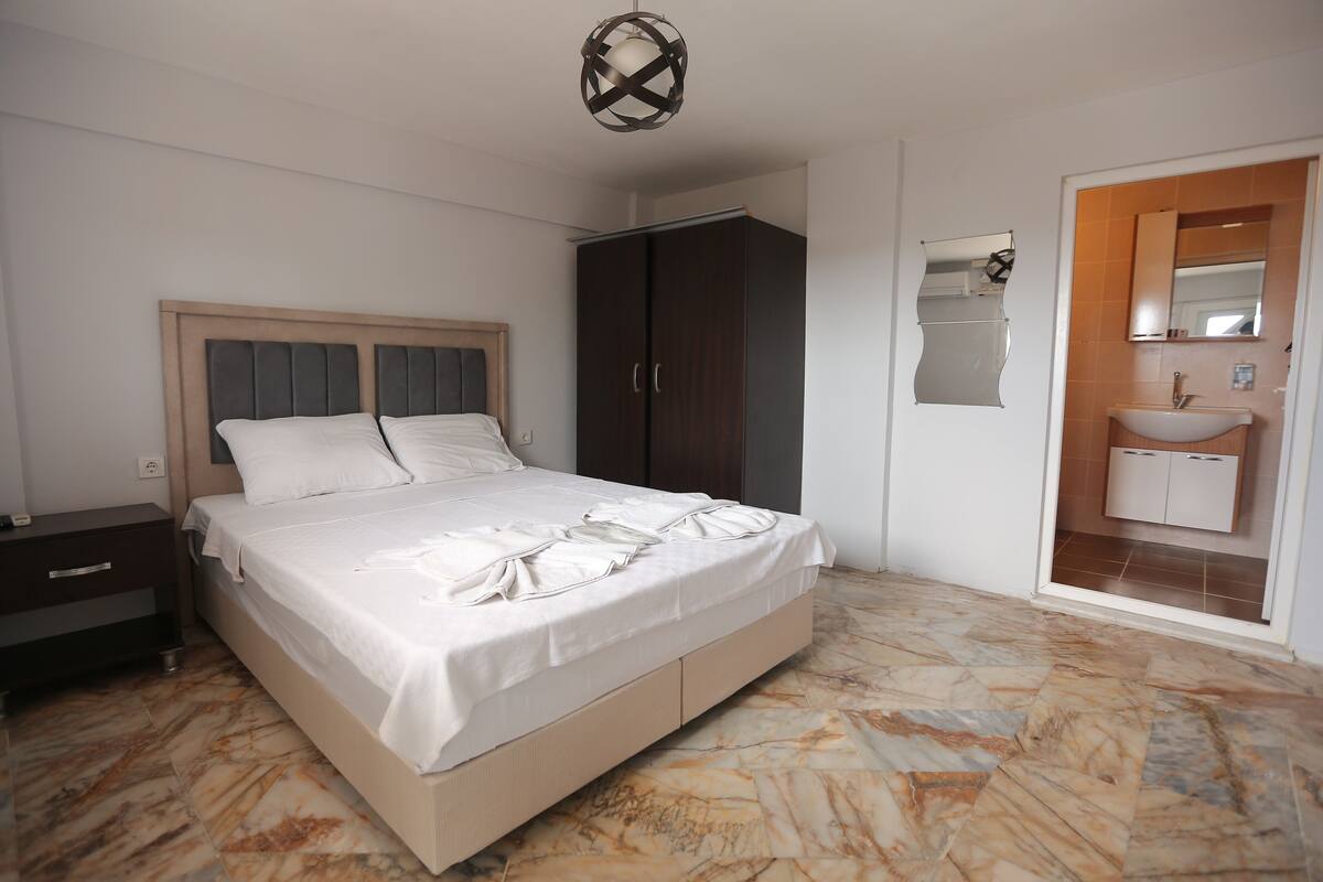 Ein Schlafzimmer mit Bett, Kleiderschrank und einem Badezimmer mit Waschbecken und Spiegel.