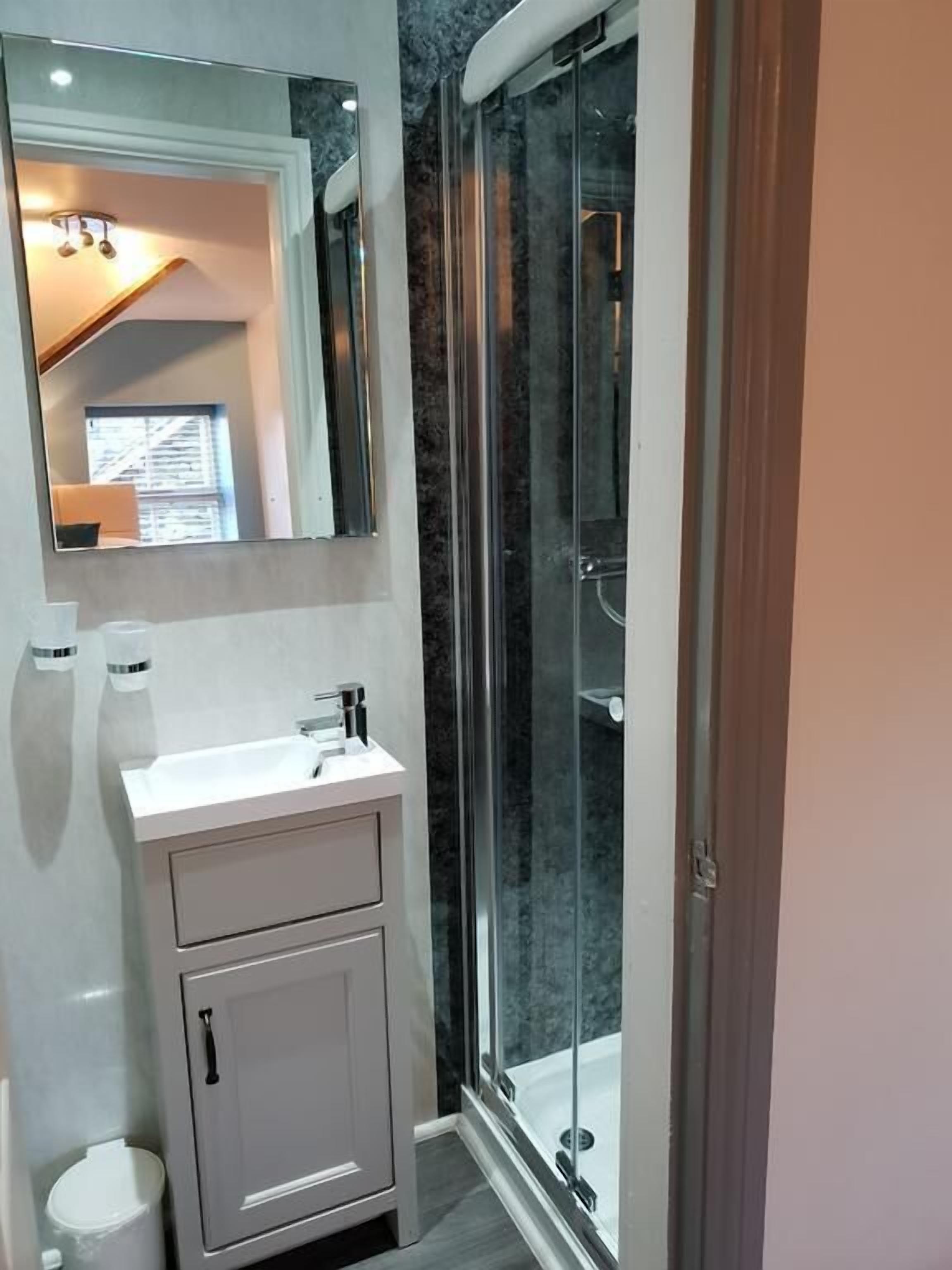 Een moderne badkamer met een douchecabine van glas, een wit wastafelmeubel en een grote spiegel.