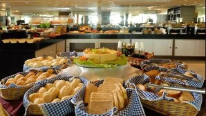 A buffet setup with various breads, a central salad, and condiments. - Flat Beira-Mar Nord Blue Sunset (João Pessoa)