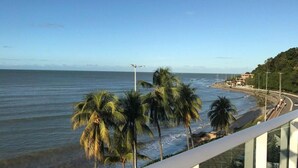 A coastal view with palm trees, a beach, and a road. - Flat Beira-Mar Nord Blue Sunset (João Pessoa)