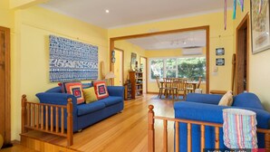 A living room with a blue sofa set, a wooden coffee table, a bookshelf, and a dining area with wooden chairs and a table. - Heyley Haven, the perfect family getaway. (VENTNOR)