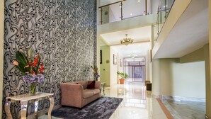 A spacious lobby with a modern design, featuring a patterned wall, a sofa, a coffee table, and a chandelier. - Sherbourne Hotel (Kitwe)