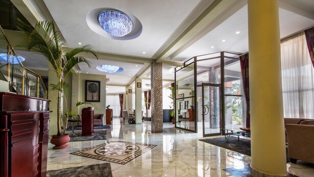 A spacious lobby with a marble floor, a large chandelier, and a reception desk. - Sherbourne Hotel (Kitwe)