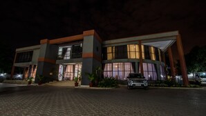 A modern two-story building with a curved facade, large windows, and a car parked in front. - Sherbourne Hotel (Kitwe)